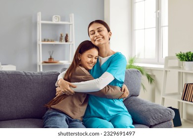 Happy child hugs doctor. Happy, smiling woman pediatrician in uniform and little girl patient sitting on couch at home and hugging. Healthcare, home visit, love, care, help, support, gratitude concept - Powered by Shutterstock