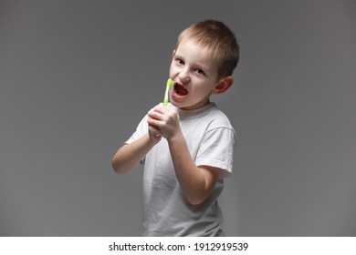 Happy Child Kid Boy Brushing Teeth With Toothbrush On Gray Background. Health Care, Dental Hygiene. Mockup, Copy Space.