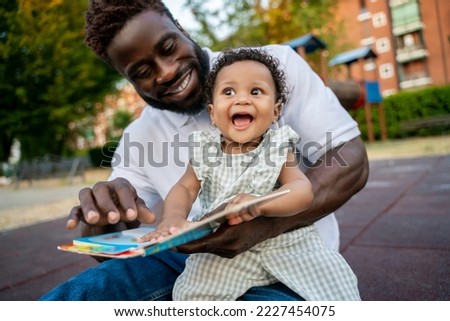 Happy child learning to read assisted by her parent