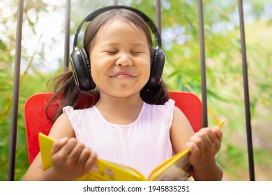 A Happy Child Listening To Music Outside And Reading A Book. Arts And Literature. 