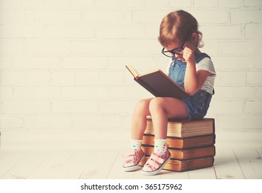 happy child little girl with glasses reading a books - Shutterstock ID 365175962
