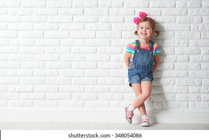 Happy child little girl laughing at a blank empty brick wall - Shutterstock ID 348054086
