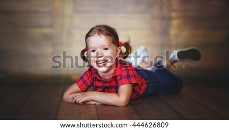 happy child little girl laughing at empty wooden wall