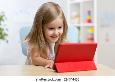 happy child little girl using tablet computer sitting at table