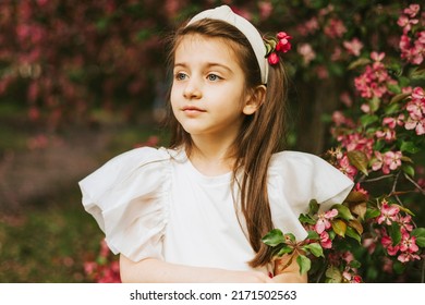 happy child little pretty armenian girl toddler walk in an apple blossoming pink garden, portrait in a spring park among flowering blooming trees, kid having fun and smiling