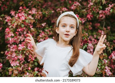happy child little pretty armenian girl toddler walk in an apple blossoming pink garden, portrait in a spring park among flowering blooming trees, kid having fun and smiling