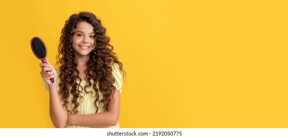 happy child with long curly hair holding comb hairbrush for combing, beauty. Kid girl hair care, horizontal poster. Banner header with copy space. - Shutterstock ID 2192050775