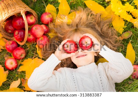 Happy child lying on fall leaves. Funny kid outdoors in autumn park