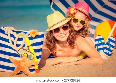 Happy Child And Mother Lying On The Beach. Summer Vacation Concept