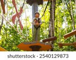 Happy child on rope climbing entertainment complex. brave little boy in helmet climbing at adventure park in autumn season. Work out concept