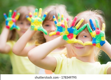 Happy child with painted hands against green spring background - Powered by Shutterstock