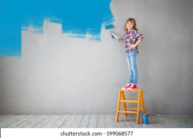 Happy Child Painting The Wall With Blue Color. Kid Having Fun At Home. Spring Renovation Concept