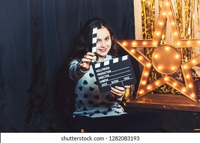 Happy Child Play With Movie Clapper Or Clapperboard. Little Girl Smile In Film Studio At Golden Star With Light Bulbs. Movie And Film Production. Imagination Game And Creativity Concept.