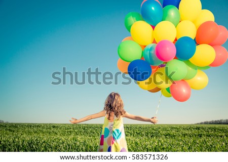 Happy child playing with balloons outdoor. Kid having fun in spring field