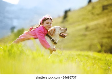 Happy Child Playing With Dog In Green Field