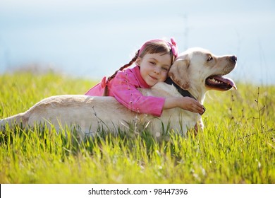 Happy Child Playing With Dog In Green Field