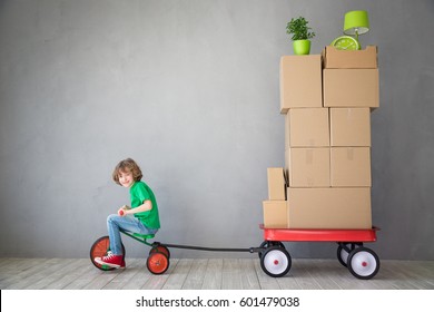 Happy Child Playing Into New Home. Kid Having Fun Indoor. Courier Riding Tricycle. Moving House Day And Express Delivery Concept