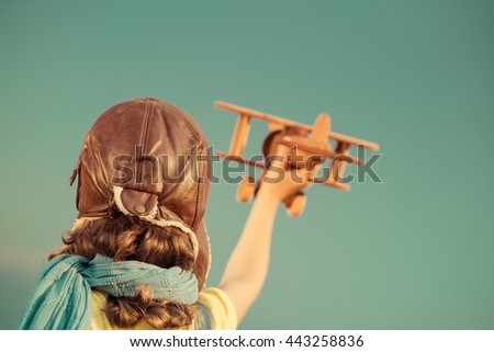 Happy child playing. Kid with toy airplane. Child having fun outdoors. Unusual portrait of kid  against summer sky background. Travel, dream and imagination concept