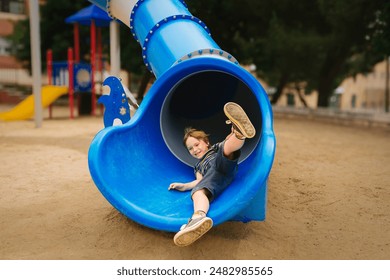 Happy Child Playing on Blue Slide in Playground - Powered by Shutterstock