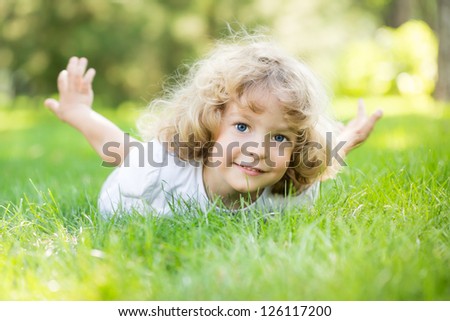 Littel girl sitting on grass looking curious