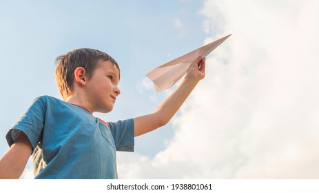 Happy Child Playing With Paper Airplane Against The Sky. A Boy With Paper Airplane.