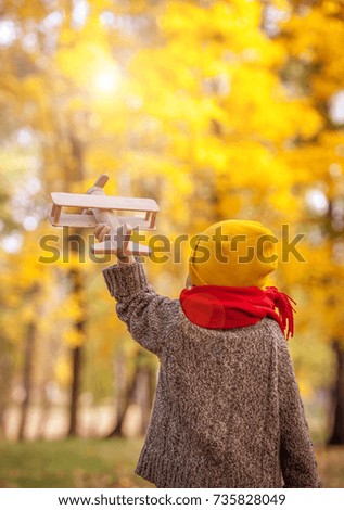 Happy child playing pilot aviator walking in autumn park. Dreams of traveling in nature . Healthy smiling boy. Back view. Colorful and bright nature. Family outdoors.  