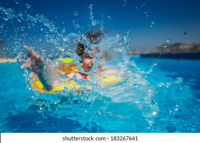 Happy Child Playing In Swimming Pool. Summer Vacations Concept. Focus On Splash