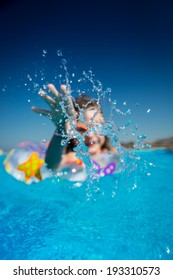 Happy Child Playing In Swimming Pool. Summer Vacation Concept. Focus On Splash