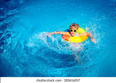 Happy child playing in swimming pool. Summer vacation concept. Top view portrait