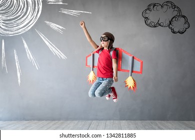 Happy child playing with toy jetpack. Kid pilot having fun at home. Success, innovation and leader concept - Powered by Shutterstock