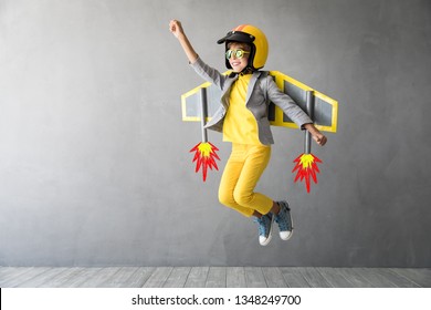 Happy child playing with toy jetpack. Kid pilot having fun at home. Success, innovation and leader concept - Powered by Shutterstock