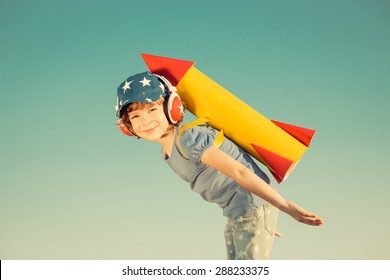 Happy Child Playing With Toy Rocket Against Summer Sky Background. Retro Toned