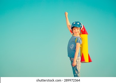 Happy Child Playing With Toy Rocket Against Summer Sky Background