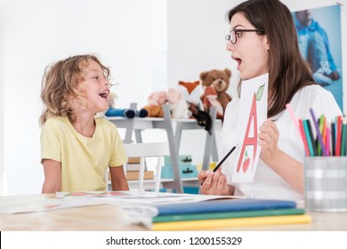 A Happy Child Pronouncing A Letter During Speech Therapy With A Specialist.