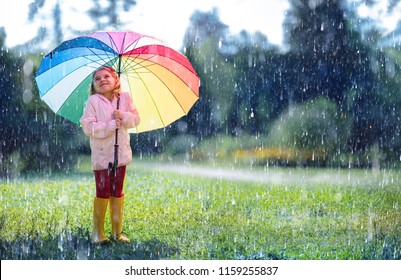 Happy Child With Rainbow Umbrella Under Rain