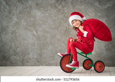 Happy Child Rides A Bike. Kid Playing At Home. Christmas Xmas Winter Holiday Concept