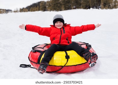 Happy child rides snow tubing (inflatable sled) in winter in the mountains - Powered by Shutterstock