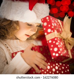 Happy Child In Santa Hat Opening Christmas Gift Box