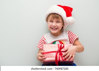 Happy Child In Santa Red Hat Holding Christmas Present. Christmas Time.
