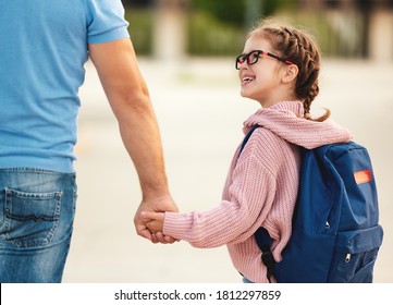Happy child schoolgirl smiles and holds his father's hand on the way to school  on the first sunny day of class - Shutterstock ID 1812297859