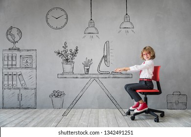 Happy Child Sitting At The Desk In Imaginary Office. Business Or Education Concept