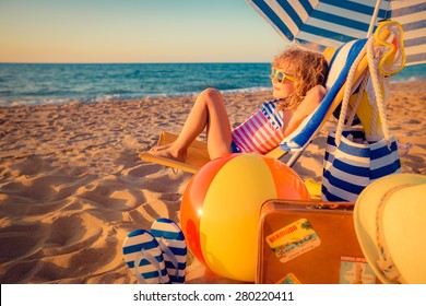 Happy child sitting on the sunbed. Funny kid at the beach. Summer vacation concept