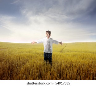 Happy Child Standing With Open Arms On A Wheat Field