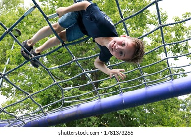 Happy Child Training Over Netting Obstacle Course In Park