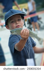 Happy Child With A Trout In His Hand While Fishing Competition