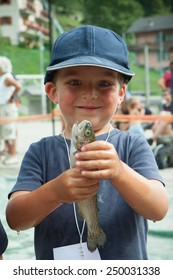 Happy Child With A Trout In His Hand While Fishing Competition