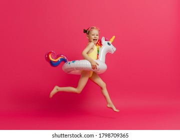 Happy Child Wearing Swimsuit. Girl With Swimming Ring Flamingo. Kid On A Colored Pink Background.