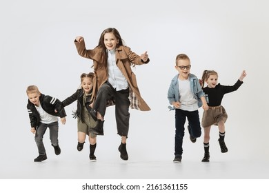 Happy Childhood. Emotional School And Preschool Age Children, Girls And Boys Running, Jumping Isolated On Grey Studio Background. Beauty, Kids Fashion, Ad, Education, Friendship Concept.