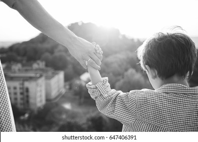 Happy childhood moment. Mother holding son by the hand - black and white.