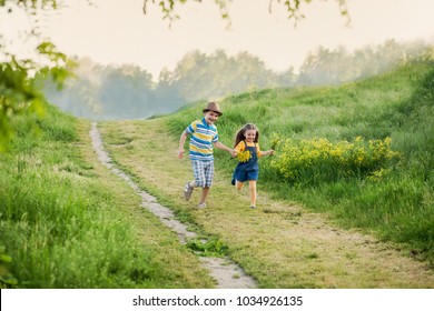 happy children, 8 year old boy and 5 year old girl, hold hands and run down the path, in the hands of children holding yellow flowers, street, spring, evening